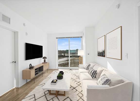 Model Living Room with Wood-Style Flooring and Patio Accessibility at Stella Apartments located in New Carrollton, MD.