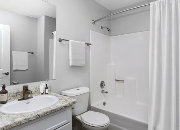 Model Bathroom with White Cabinets, Wood-Style Flooring and Shower/Tub at The Meritage Apartments in Vallejo, CA.