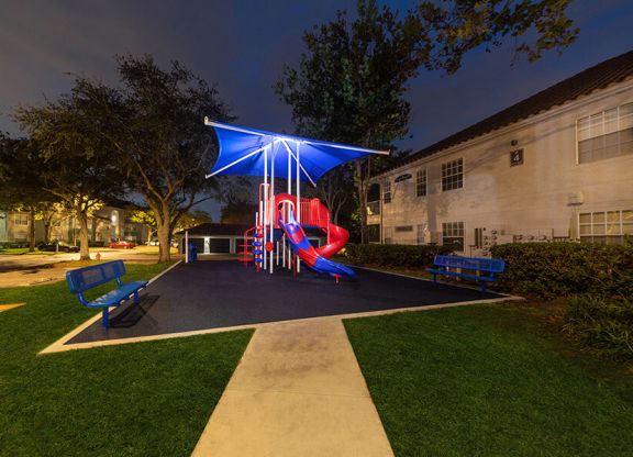 Community Playground with Slide and Blue Canopy at Vinings at Hunter's Green Apartments in Tampa, FL.