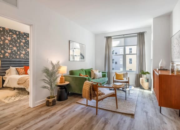 Model living room with a green couch and a large window