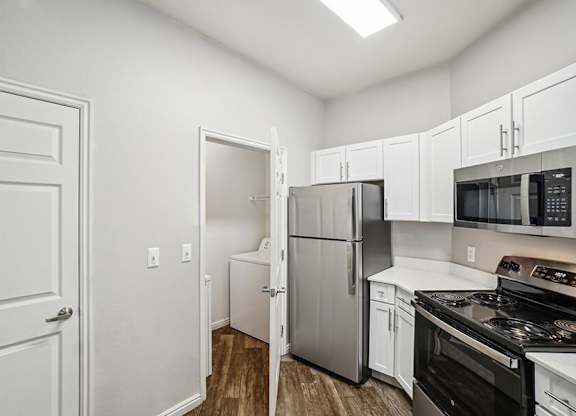Model Kitchen with Wood-Style Flooring, White Cabinets, and Stainless-Steel Appliances at Altitude on Fifth Apartments located in Salt Lake City, UT.
