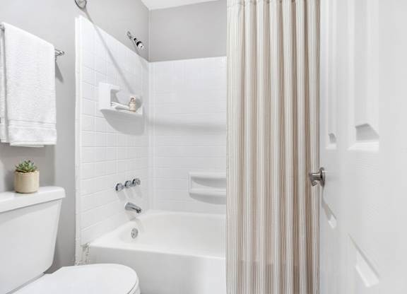 A white bathroom with a towel hanging on the towel rack.