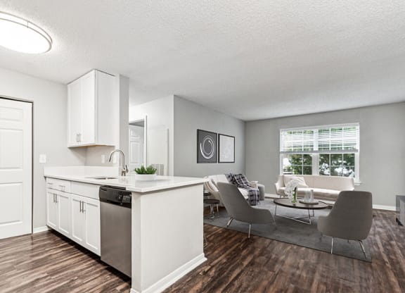 Model Kitchen with White Cabinets, Wood-Style Flooring and View of Living Room at Commons at Haynes Farm Apartments in Shrewsbury, MA.