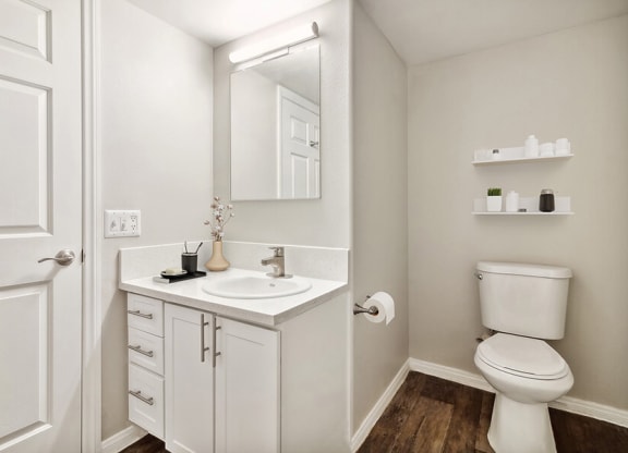 Model Bathroom with Wood-Style Flooring and White Cabinets at Loma Vista Apartments in Las Vegas, NV.