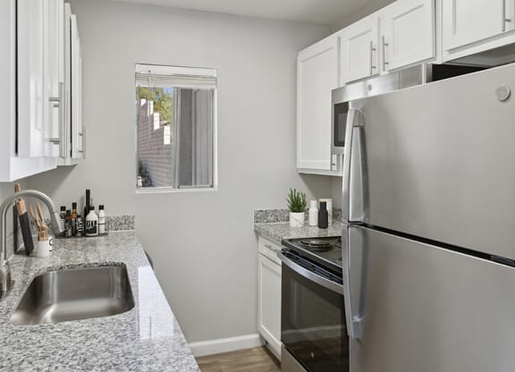 Model Kitchen with White Cabinets and Wood-Style Flooring at Hilands Apartments in Tucson, AZ.
