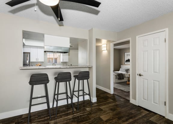 a kitchen with a breakfast bar and three stools in front of it at Villages at Metro Center, Phoenix, AZ
