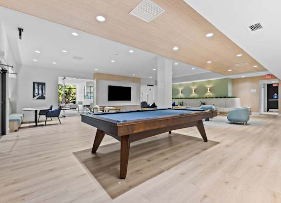 A pool table is in the middle of a room with a wooden floor.