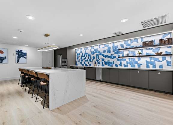 A kitchen with a white counter and a blue and white tiled wall.