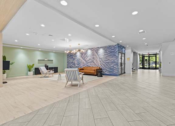 A spacious lobby with a blue and white abstract wall art, a wooden bench, and a blue sofa.