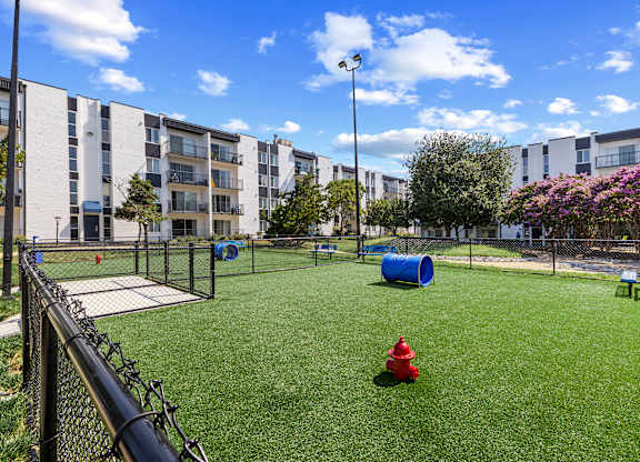 A red fire hydrant sits on a green lawn in a courtyard.