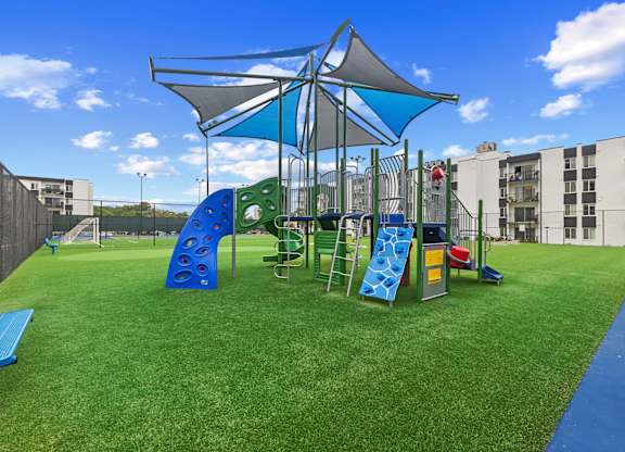 A playground with a blue slide and rockwalland a green slide.