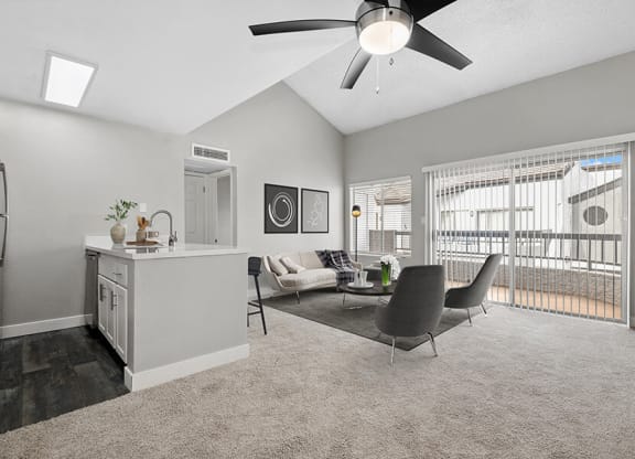 Model Living Room with Carpet and View of Kitchen with Wood-Style Flooring at Crystal Creek Apartments in Phoenix, AZ.