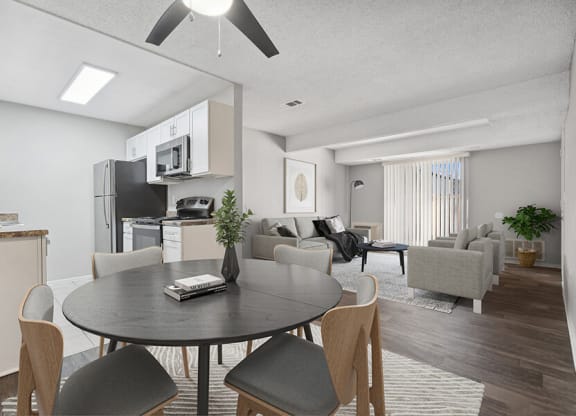 Model Dining Room with Wood-Style Flooring and View of Kitchen/Living Room at Liberty Creek Apartments in Aurora, CO.