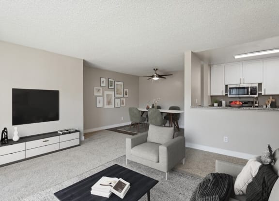 Model living room with a flat screen tv and a kitchen in the background