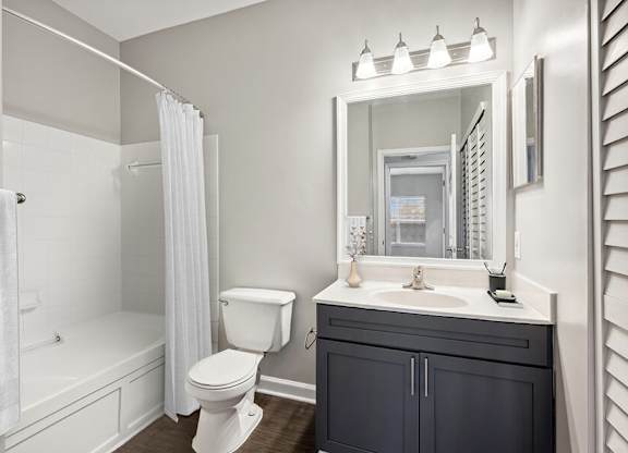 Model Bathroom with Dark Wood Cabinets and Wood-Style Flooring at Dulles Green Apartments located in Herndon, VA.