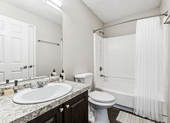 Model Bathroom with Dark Cabinets, Wood-Style Flooring and Shower/Tub at Paramont Apartments in Duluth, GA.
