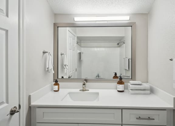 Model Bathroom with White Cabinets and Wood-Style Flooring at Arbor Village Apartments located in Charlotte, NC.