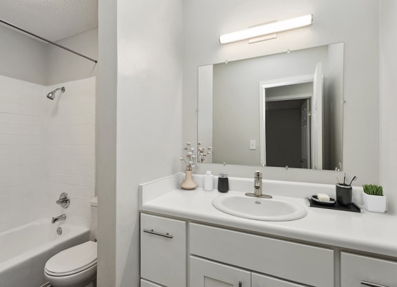 Model Bathroom with White Cabinets, Wood-Style Flooring and Shower/Tub at Parc at Creekside Apartments in Kansas City, MO.