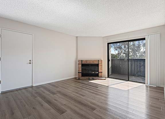 Model Living Room with Wood-Style Flooring, Fireplace and Patio Accessibility at Santa Fe Ranch Apartments located in Carlsbad, CA.