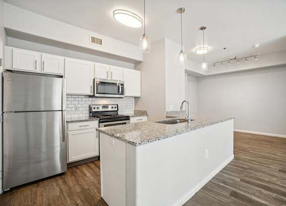 Model Kitchen with Wood-Style Flooring, White Cabinets, and Stainless-Steel Appliances at Altitude on Fifth Apartments located in Salt Lake City, UT.