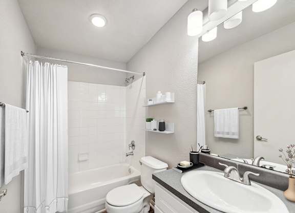 Model Bathroom with White Cabinets, Wood-Style Flooring and Shower/Tub at Lake Cameron Apartments located in Apex, NC.