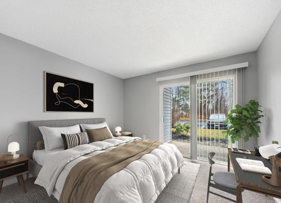 Model Bedroom with Carpet and Patio Accessibility at Commons at Haynes Farm Apartments in Shrewsbury, MA.