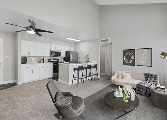 Model Living Room with Carpet and View of Kitchen with Wood-Style Flooring at Crystal Creek Apartments in Phoenix, AZ.