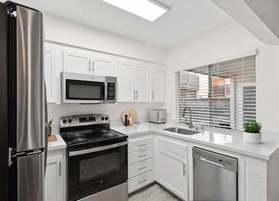 Model Kitchen with White Cabinets and Wood-Style Flooring at Horizon Apartments located in Santa Ana, CA.
