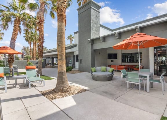 a patio with chairs and umbrellas in front of a building