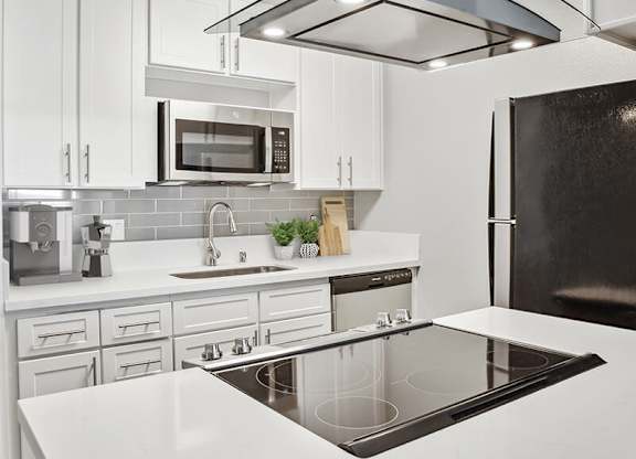 Model Kitchen with White Cabinets and Wood-Style Flooring at Cove La Mesa Apartments located in La Mesa, CA.