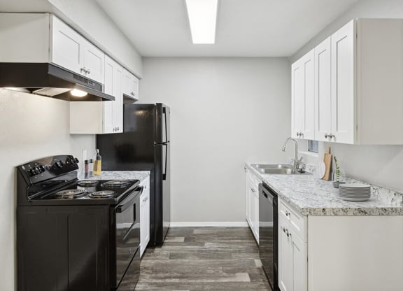 Model Kitchen with White Cabinets and Wood-Style Flooring at Tanque Verde Apartments located in Tucson, AZ.