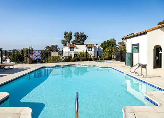 A swimming pool in a residential area with a house and trees in the background.