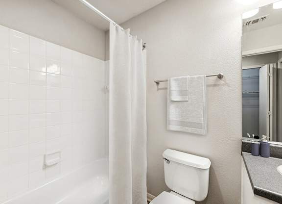 Model Bathroom with White Cabinets, Wood-Style Flooring & Shower/Tub at Lake Cameron Apartments located in Apex, NC.