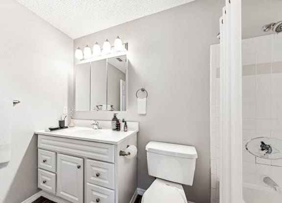 Model Bathroom with White Cabinets, Wood-Style Flooring and Shower/Tub at Commons at Haynes Farm Apartments in Shrewsbury, MA.