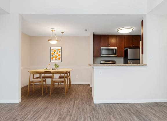 Model Dining Room and Kitchen Area with Wood-Style Flooring at The Commons at Haynes Farm Apartments in Boston, MA.