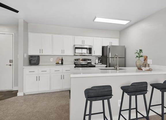 Model Kitchen with White Cabinets and Wood-Style Flooring at Crystal Creek Apartments in Phoenix, AZ.