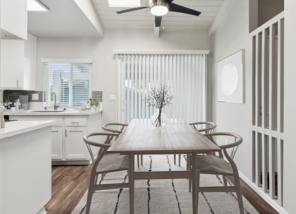 Model Dining Room and Kitchen Area with Wood-Style Flooring and Patio Accessibility at Colonnade at Fletcher Hills Apartments in El Cajon, CA.