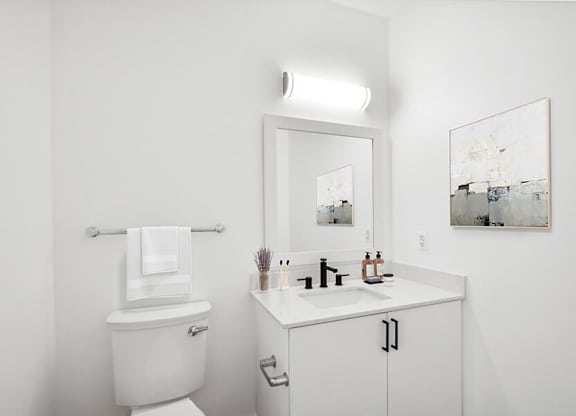 Model Bathroom with White Cabinets, Wood-Style Flooring and Shower/Tub at Stella Apartments located in New Carrollton, MD.