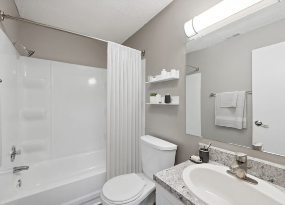 Model Bathroom with White Cabinets, Wood-Style Flooring and Shower/Tub at Spring Forest Apartments in Raleigh, NC.
