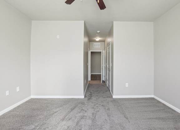 Model bedroom with a carpeted floor and a ceiling fan.