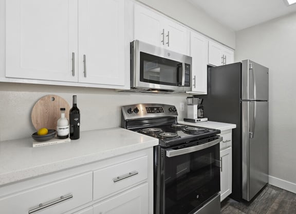 Model Kitchen with White Cabinets and Wood-Style Flooring at Crystal Creek Apartments in Phoenix, AZ.