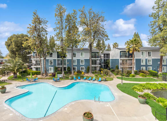 Community Swimming Pool with Pool Furniture at Fountains at Point West Apartments in Sacramento, CA.