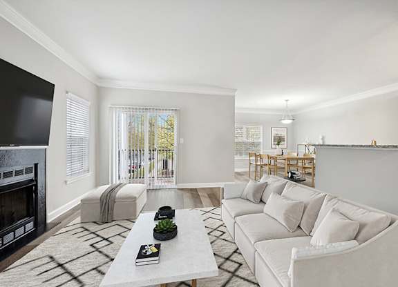Model Living Room with Wood-Style Flooring, Fireplace and Patio Accessibility at Dulles Green Apartments located in Herndon, VA.