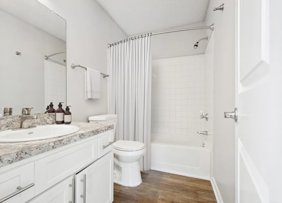 Model Bathroom with White Cabinets, Wood-Style Flooring and Shower/Tub at Westland Park Apartments in Jacksonville, FL.