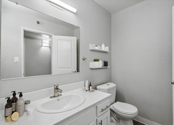 Model Bathroom with White Cabinets and Wood-Style Flooring at The Archer Apartments in Sacramento, CA.