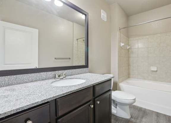 Model bathroom with a white toilet, sink, and bathtub.
