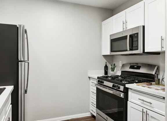 Model Kitchen with White Cabinets and Wood-Style Flooring at Loma Vista Apartments in Las Vegas, NV.