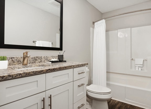Model Bathroom with Wood-Style Flooring, White Cabinets & Shower/Tub at Park 2300 Apartments in Charlotte, NC.