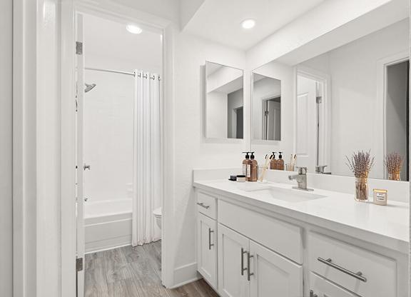 Model Bathroom with White Cabinets, Wood-Style Flooring & Shower/Tub at Horizon Apartments located in Santa Ana, CA.