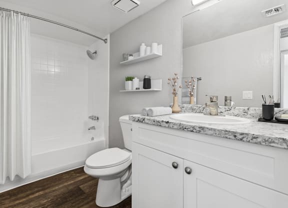 Model Bathroom with White Cabinets, Wood-Style Flooring and Tub/Shower at Tanque Verde Apartments located in Tucson, AZ.